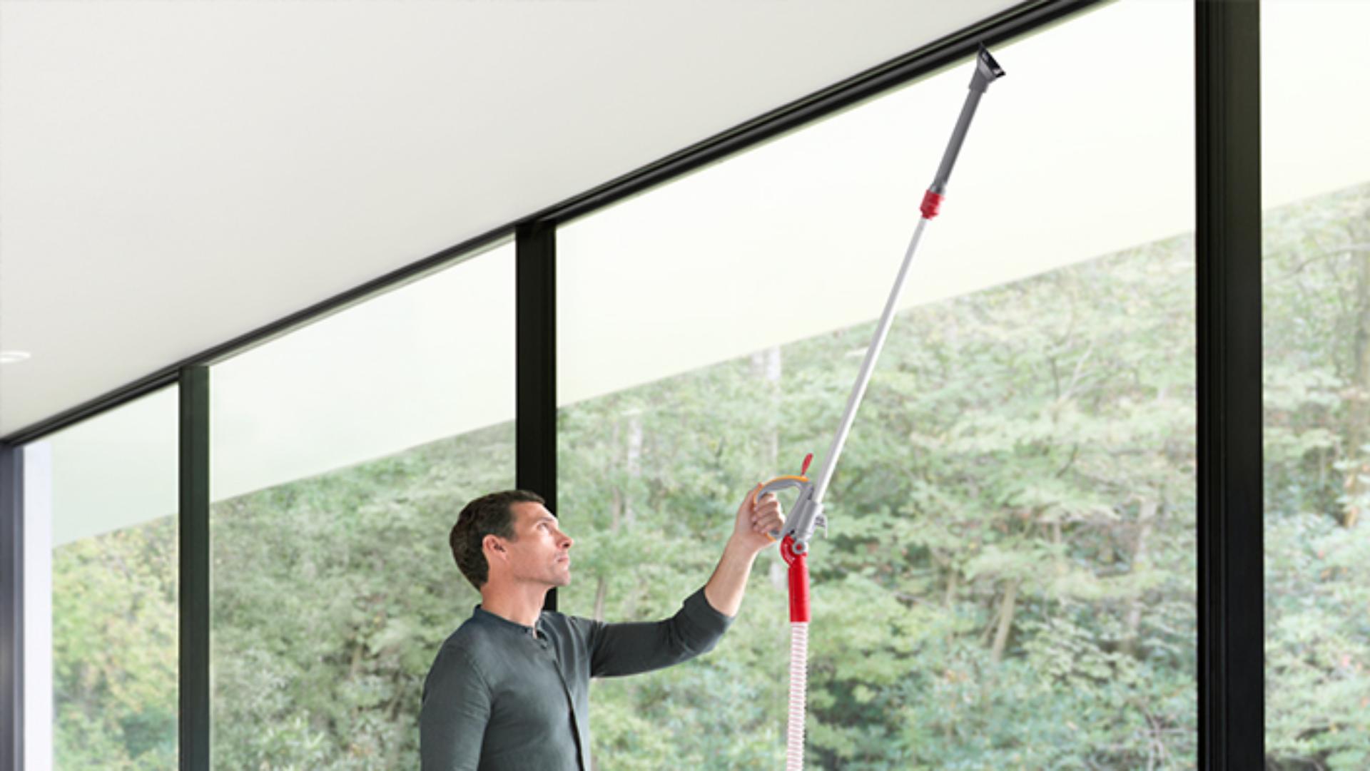 Upright vacuum cleaner being steered in a sweeping arc across a black hard floor surface.