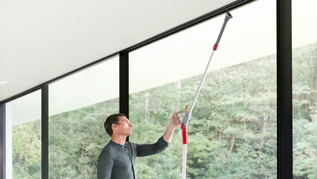 Upright vacuum cleaner being steered in a sweeping arc across a black hard floor surface.