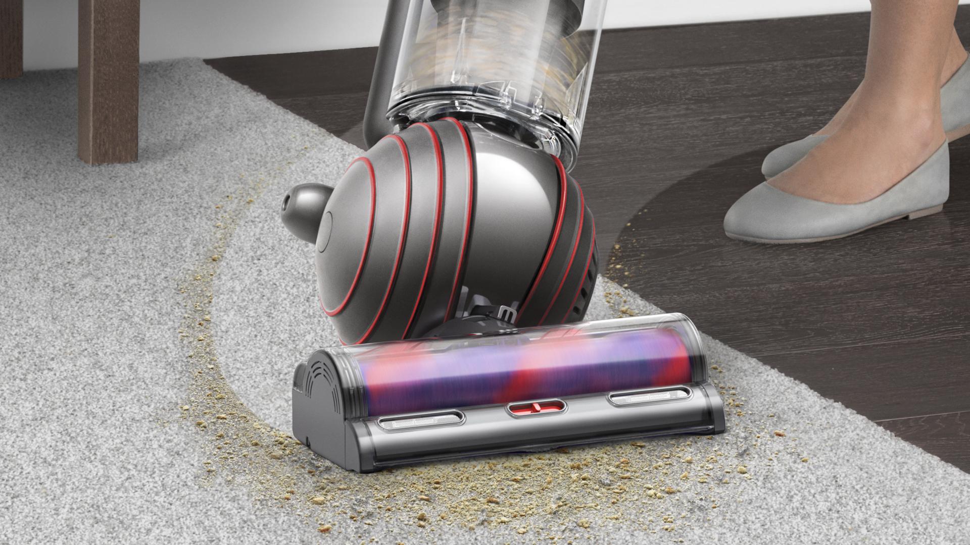 Upright vacuum cleaner being steered in a sweeping arc across a black hard floor surface.