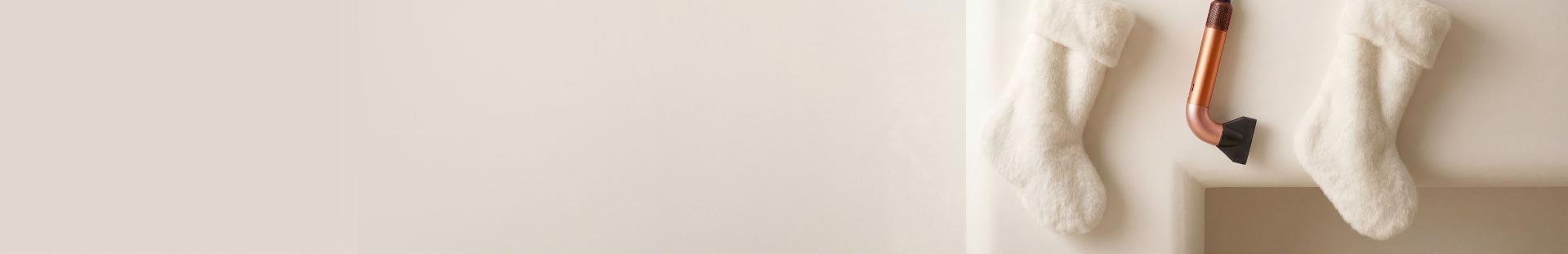 The Dyson Supersonic r hair dryer hanging in a line between a pair of Christmas stockings.