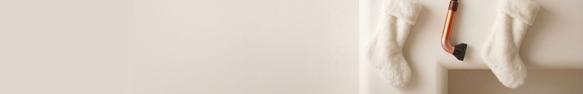 The Dyson Supersonic r hair dryer hanging in a line between a pair of Christmas stockings.