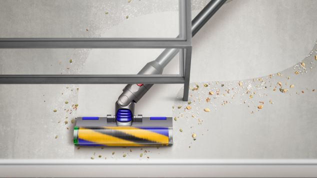 Someone cleaning under a table with the Dyson V12 Detect Slim vacuum.