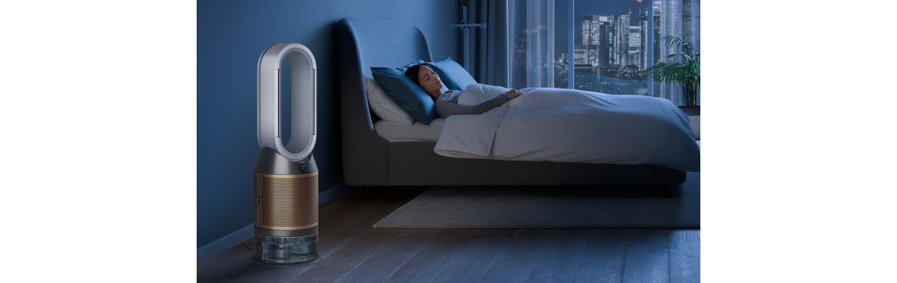 The Dyson Purifier Humidify+Cool Formaldehyde in a dark bedroom at night as a woman sleeps in her bed.