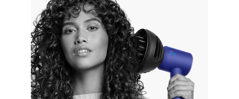 Nærbillede af en kvinde, der tilføjer volumen til sit krøllede hår med Dysons Wave+Curl diffuser.
