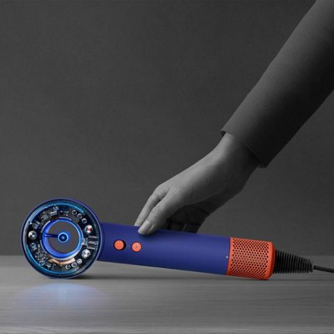 Eine Hand, die nach unten greift, um den Dyson Supersonic Nural™-Haartrockner aufzuheben