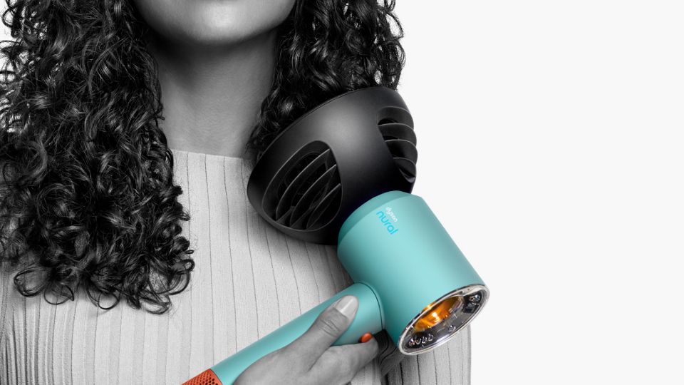Nahaufnahme einer Frau, die ihre lockigen Haarspitzen mit dem Dyson Wave+Curl Diffusor trocknet