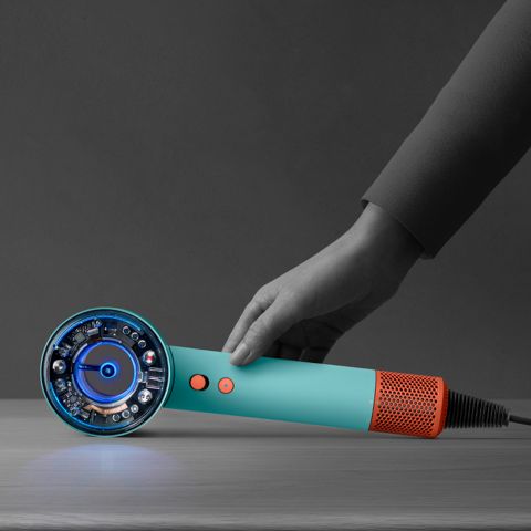 A hand reaching down to pick up the Dyson Supersonic Nural hair dryer.