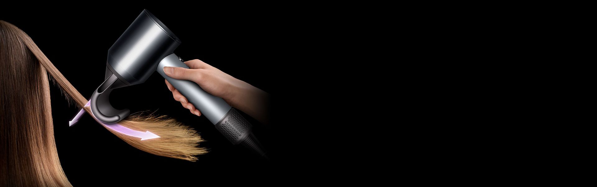 A woman hides flyaways in long brown hair using the Dyson Supersonic hair dryer and Flyaway attachment.