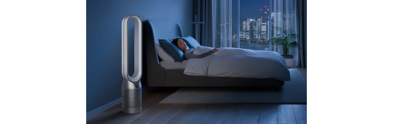 A Dyson Purifier Cool in Night mode next to a sleeping person.