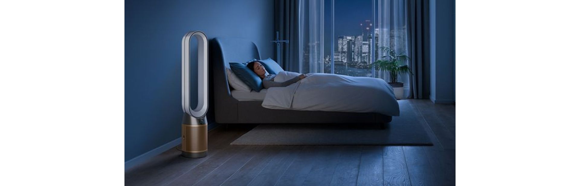 The Dyson Purifier Cool Formaldehyde in a dark bedroom at night as a woman sleeps in her bed.