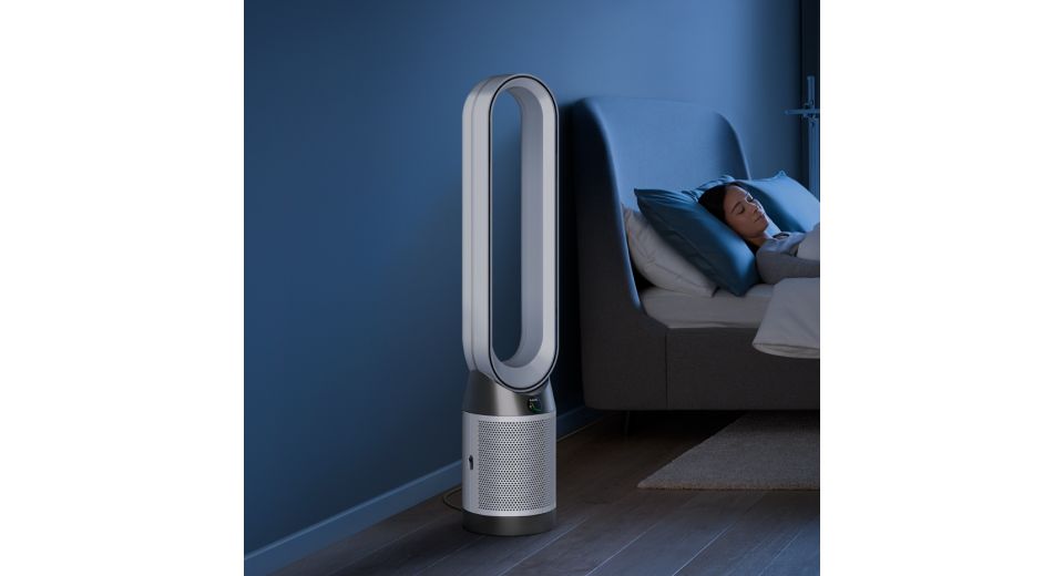 A Dyson Purifier Cool Gen1 TP10 purifying fan operates next to a person asleep in a bed.