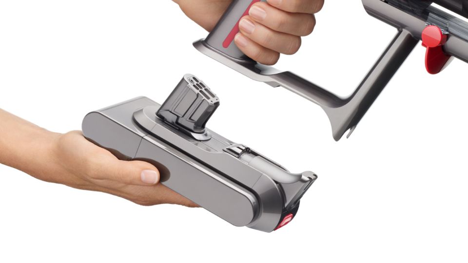 Gros plan sur une main en train d’enclencher une batterie clipsable sur l’aspirateur Dyson V15 Detect.