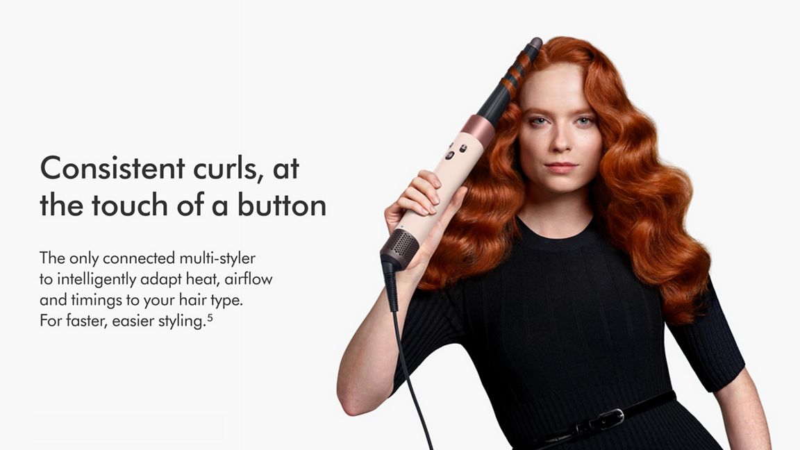 Woman curling hair with the Dyson Airwrap ID multi-styler. With consistent curls at a touch of a button text. 