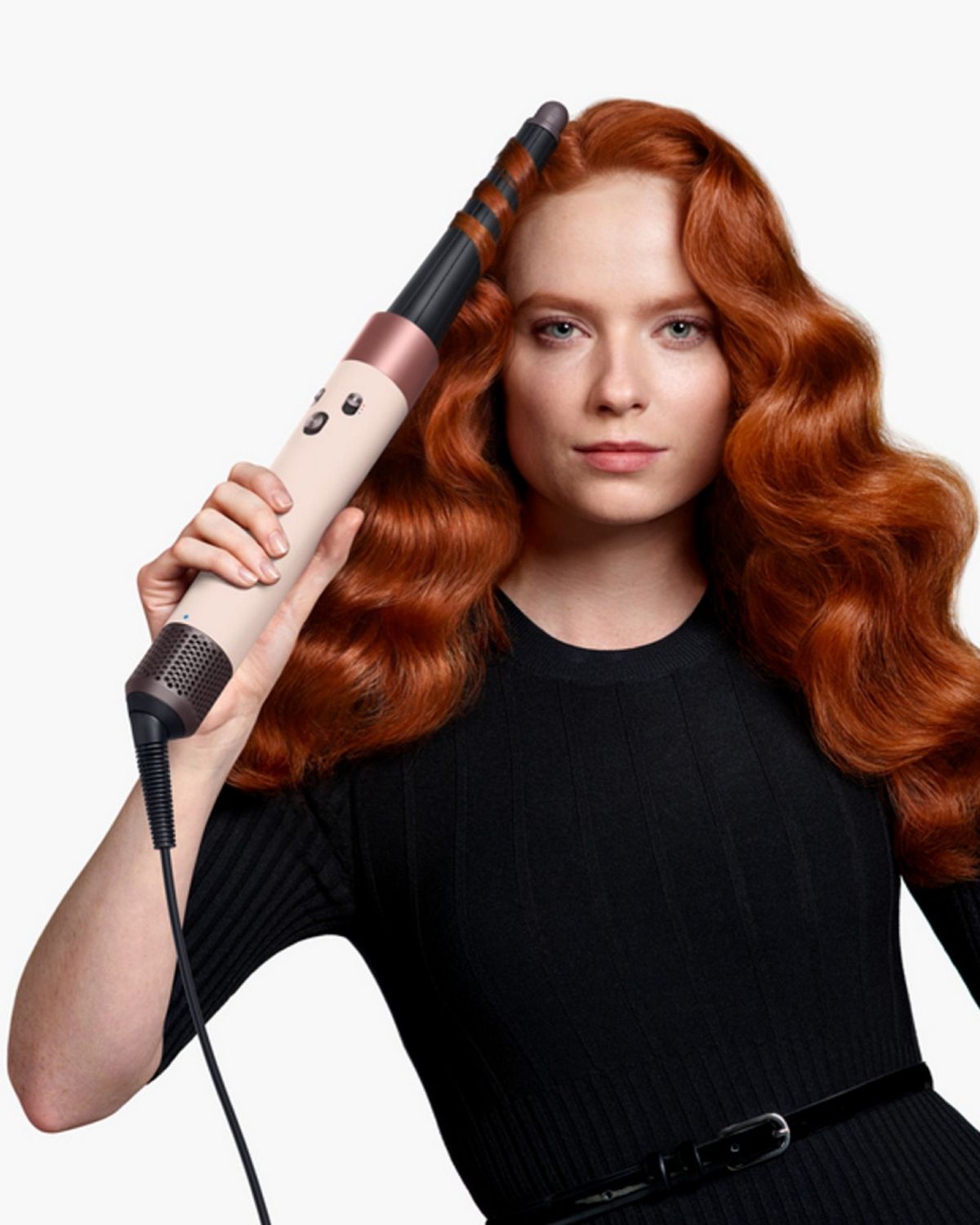 Woman curling hair with the Dyson Airwrap ID multi-styler. With consistent curls at a touch of a button text. 