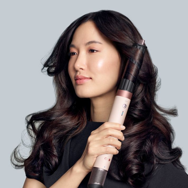 Una modella dai capelli scuri crea dei ricci usando lo styler asciugacapelli Dyson Airwrap Co-anda2x. Una modella dai capelli scuri crea dei ricci usando lo styler asciugacapelli Dyson Airwrap Co-anda2x.