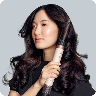 A model with dark hair adds curls using the Dyson Airwrap Co-anda2x multi-styler and dryer.