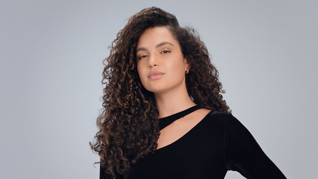 A brunette model with defined natural curls. A brunette model with defined natural curls.