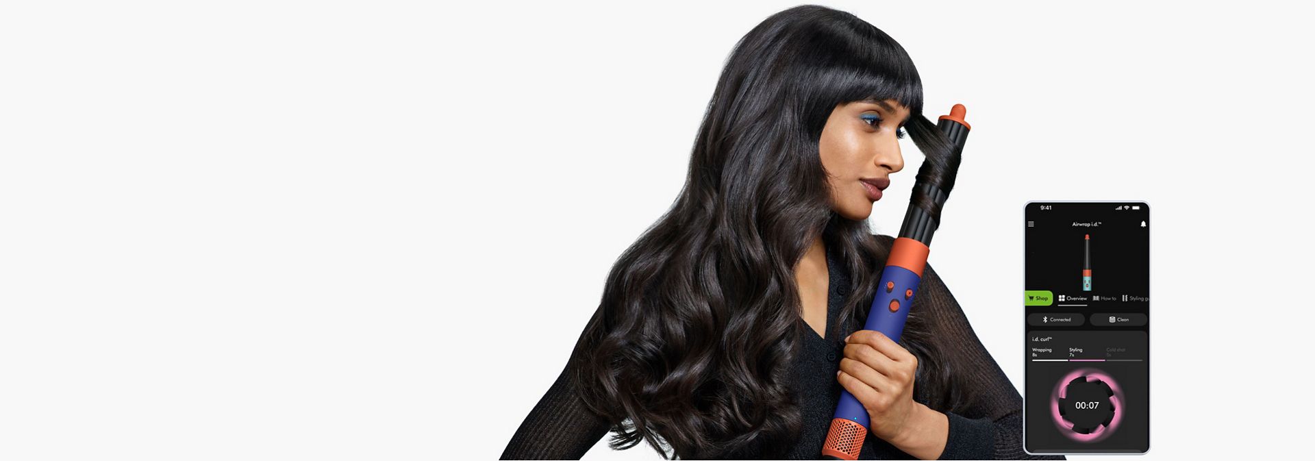 Dyson Airwrap i.d. multi-styler being used by two models, with smartphone screens showing our app.