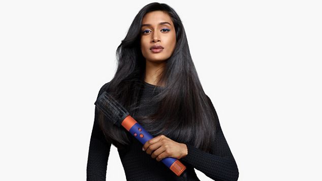 Modell med en 90-talls blow out-frisyre holder en Dyson Airwrap i.d.