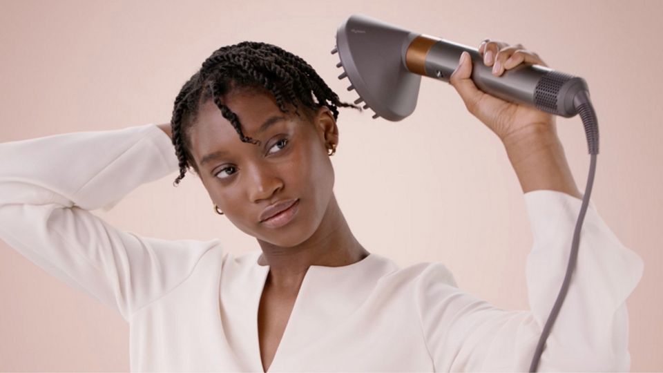 A model styling their hair with the Diffuser attachment.