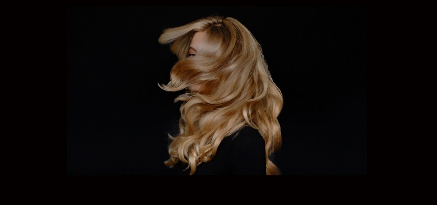 Femme blonde avec des cheveux brimllants sur un fond noir