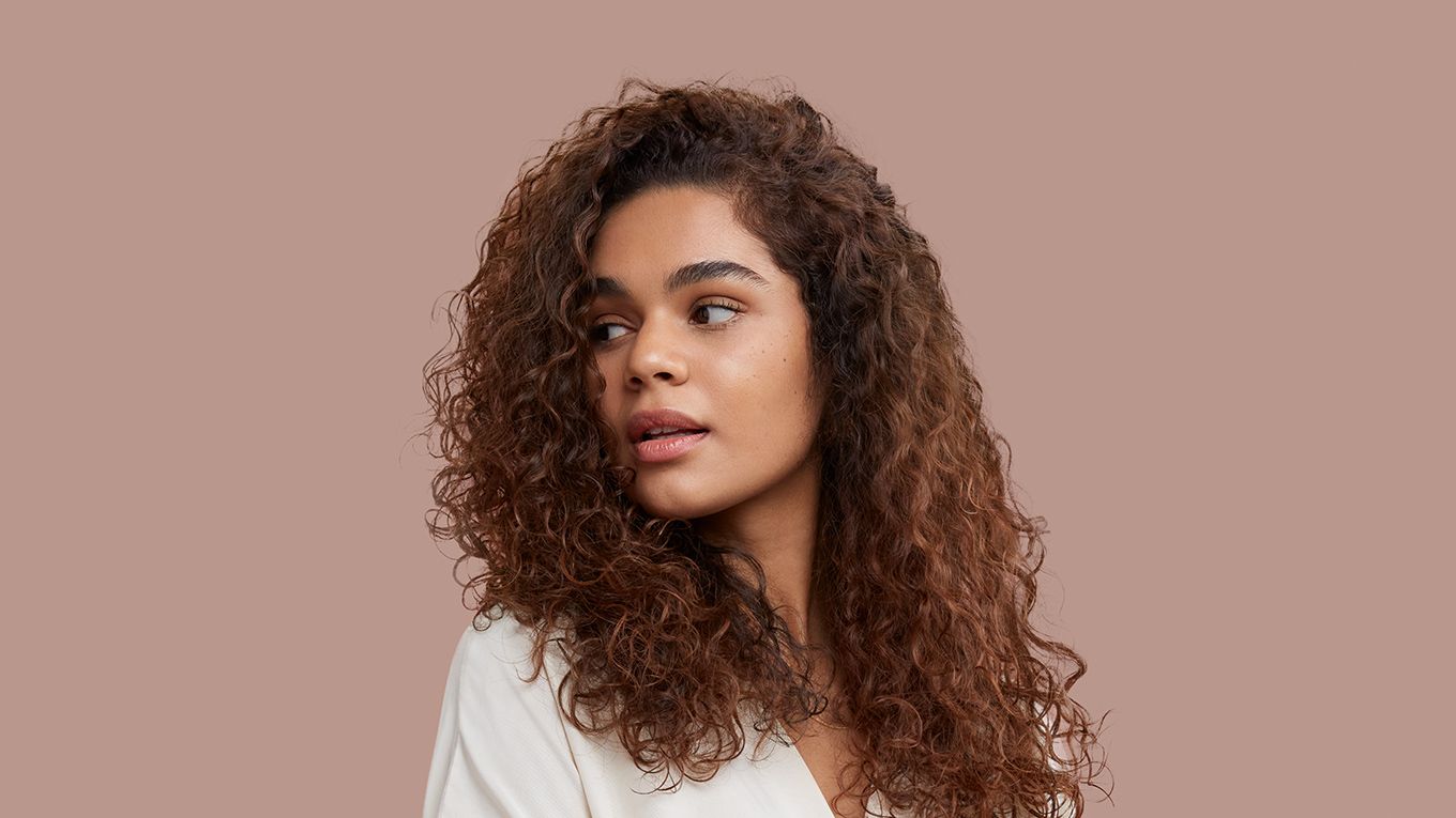 A model with light-brown curly hair styled into defined curls. A model with light-brown curly hair styled into defined curls.