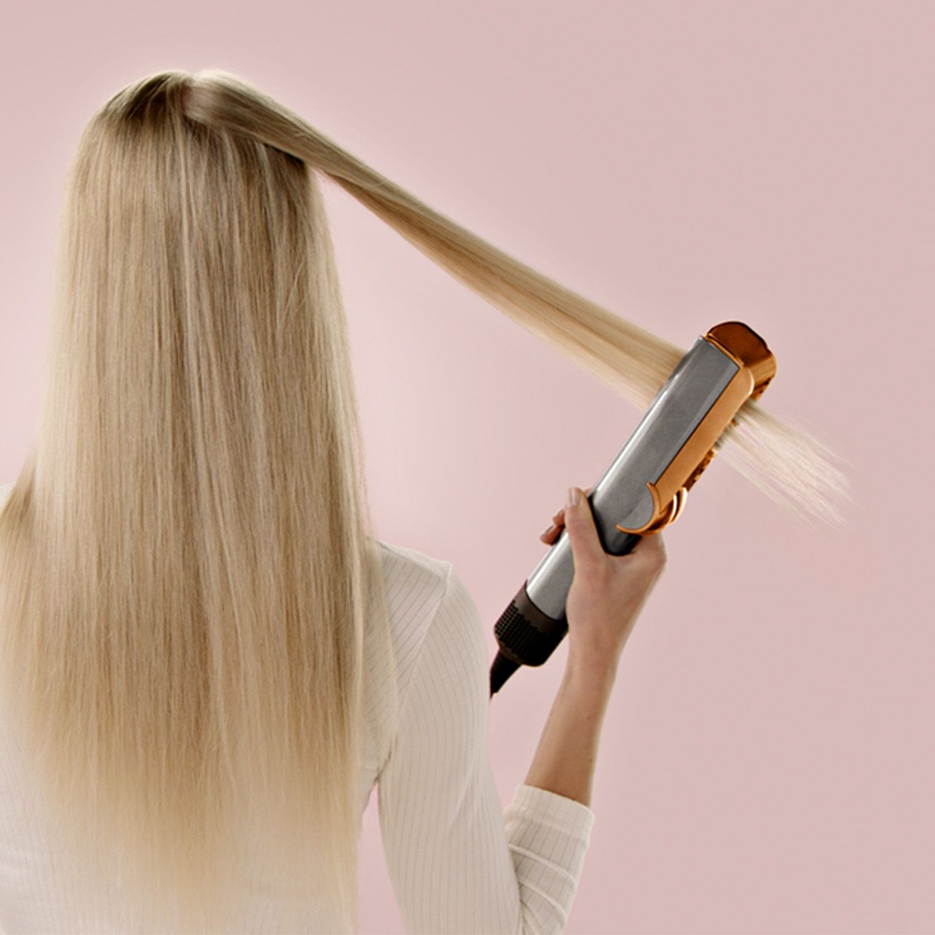 A model uses the Dyson Airstrait straightener to style her hair.
