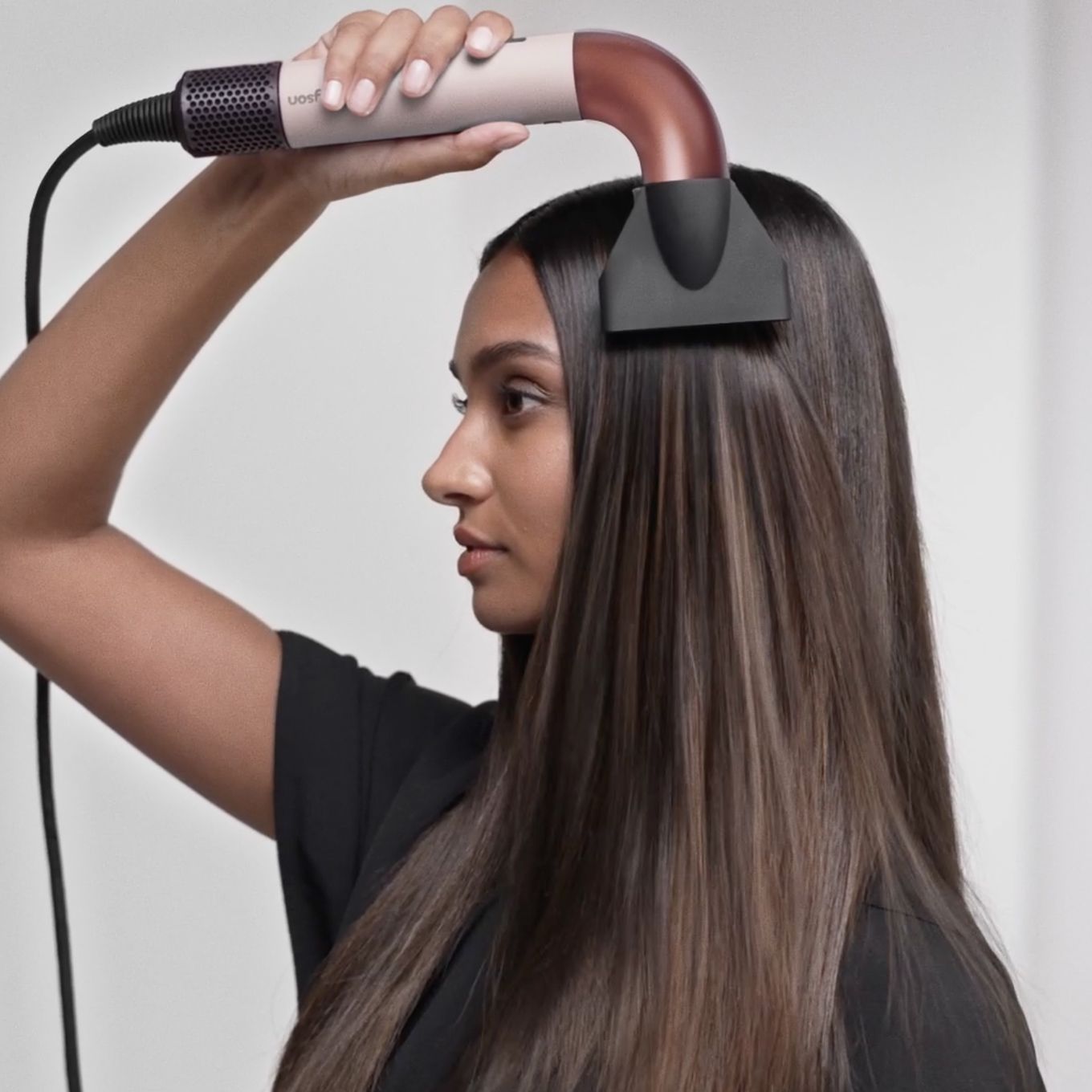Un modèle se sèche les cheveux avec le sèche-cheveux Dyson Supersonic r et le concentrateur professionnel.
