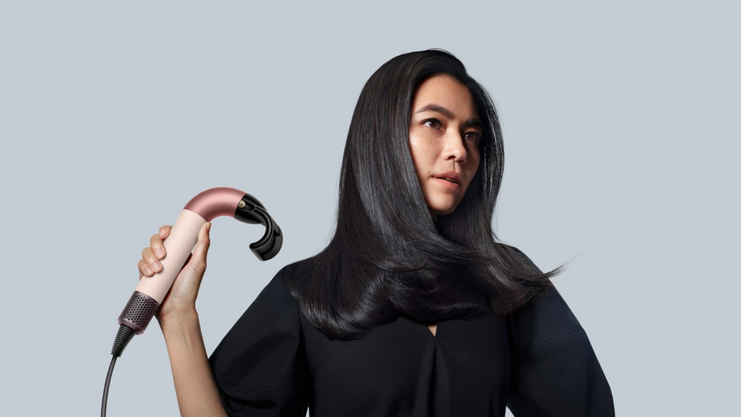 Model drying hair with the Dyson Supersonic r hair dryer and Flyaway attachment. 