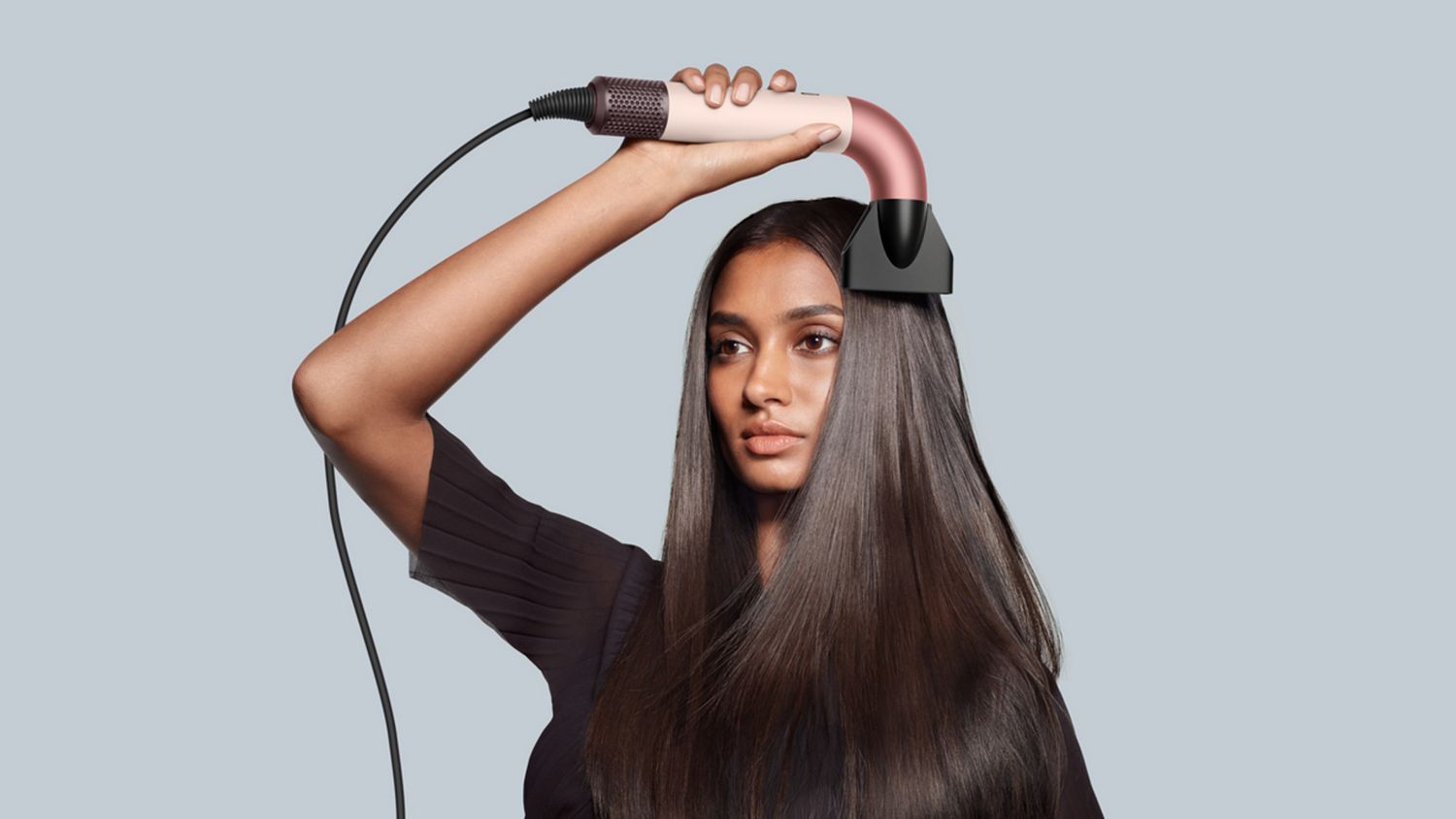 Model drying hair with the Dyson Supersonic r hair dryer and Pro concentrator attachment.