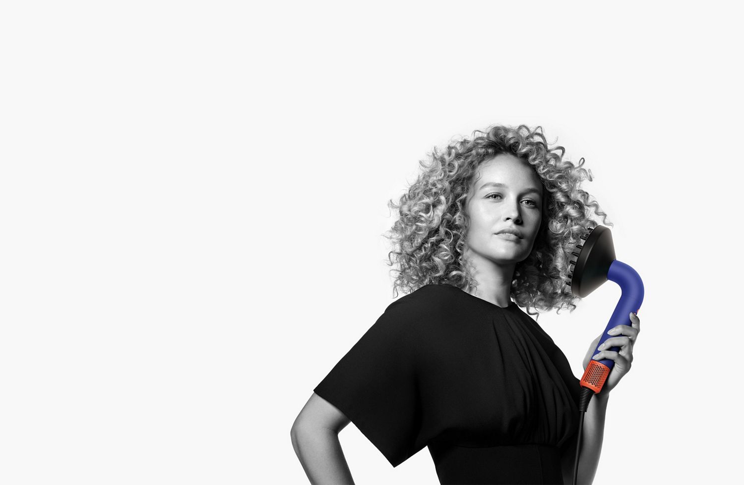 Dyson Supersonic r ヘアードライヤーを使う巻き髪の女性
