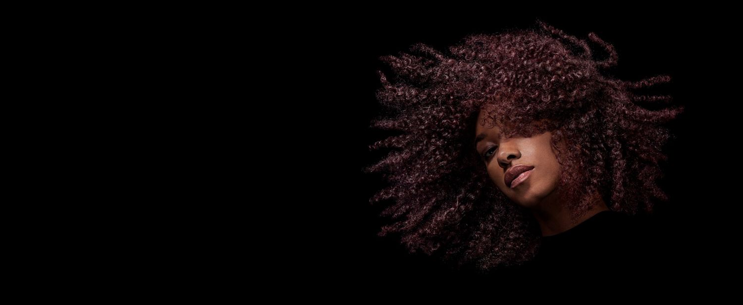 A curly haired model swishing her styled hair.