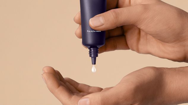 Die Dyson Chitosan Pre-Style Cream wird durch Drücken in eine Hand gegeben.