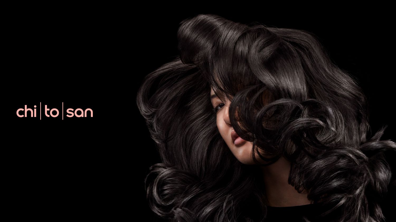 A dark-haired model with voluminous wavy hair styled with Dyson Chitosan.