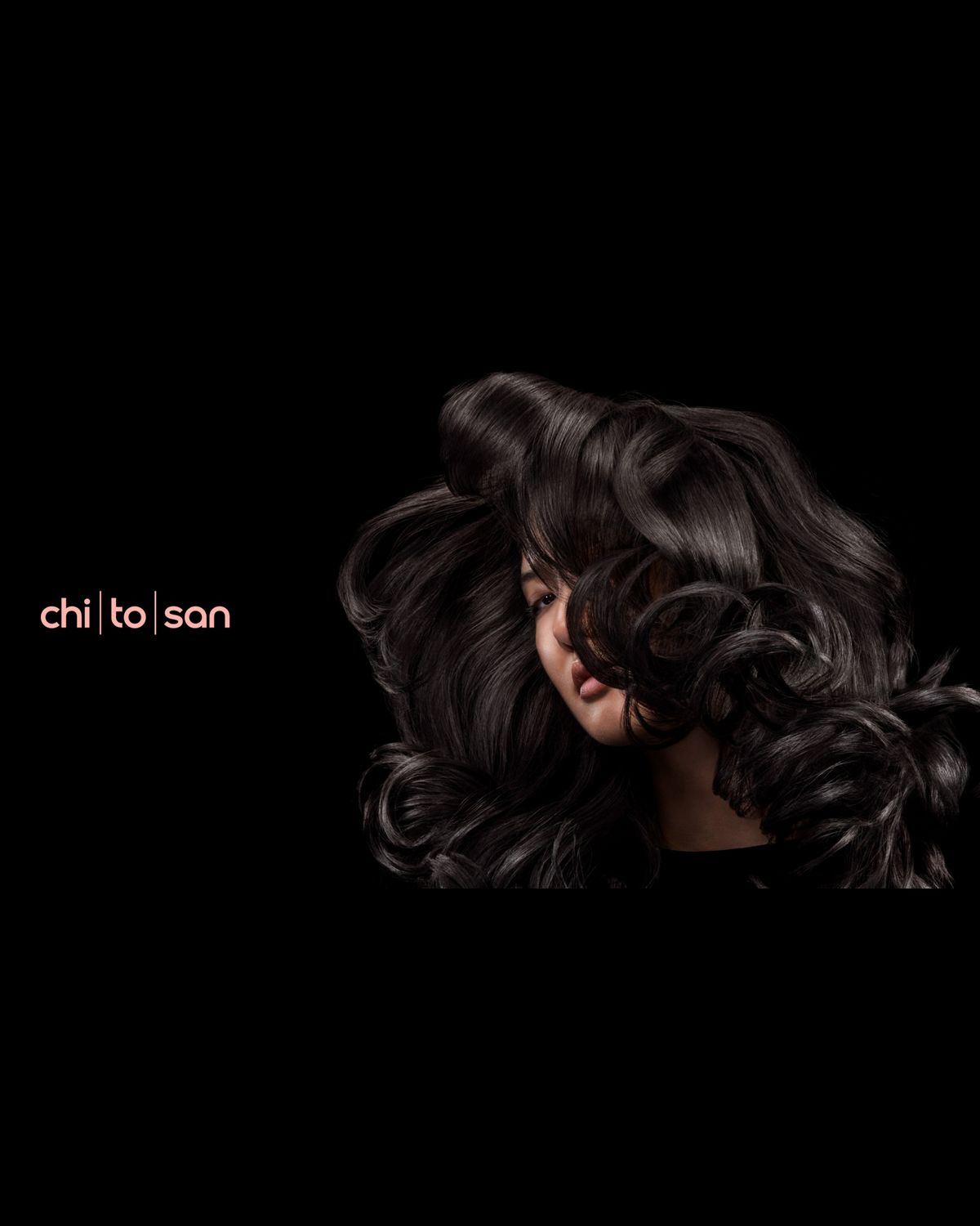 A dark-haired model with voluminous wavy hair styled with Dyson Chitosan.