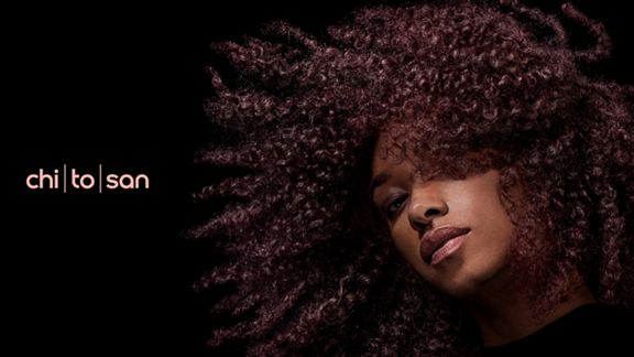 Ein brünettes Model mit voluminösen, krausen Haaren, die mit Dyson Chitosan gestylt wurden.