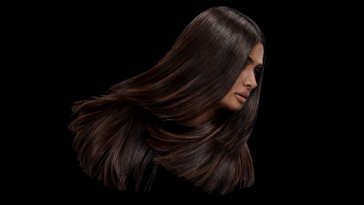 A model with brown coily hair before and after styling their hair with Dyson Chitosan Pre-style cream.