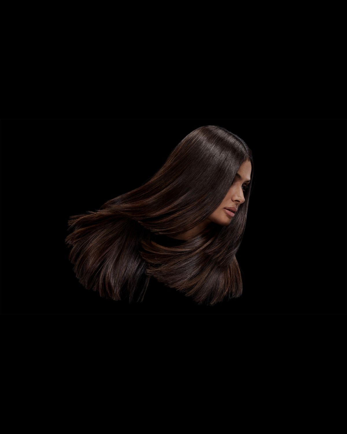 A model with brown coily hair before and after styling their hair with Dyson Chitosan Pre-style cream.