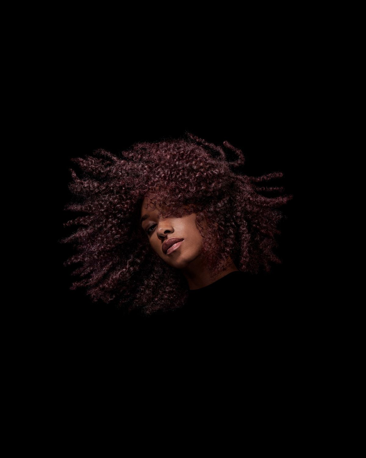 A model with dark coily hair after styling their hair with Dyson Chitosan Post-style serum.
