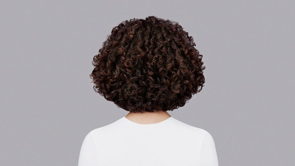 Natürlich lockiges, dunkelbraunes Haar gestyled mit der Dyson Chitosan Pre-Style Cream und dem Dyson Supersonic r.
