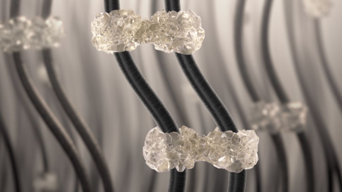 Très gros plan de mèches de cheveux assemblés par intermittence par des structures rigides d’aspect cristallin. 