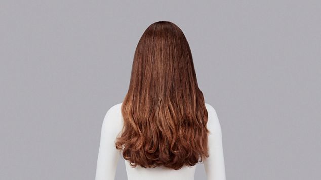 Naturlig krøllete, lysebrunt hår stylet med Dyson Chitosan Post-style-serum og Dyson Airwrap. Sett bakfra.