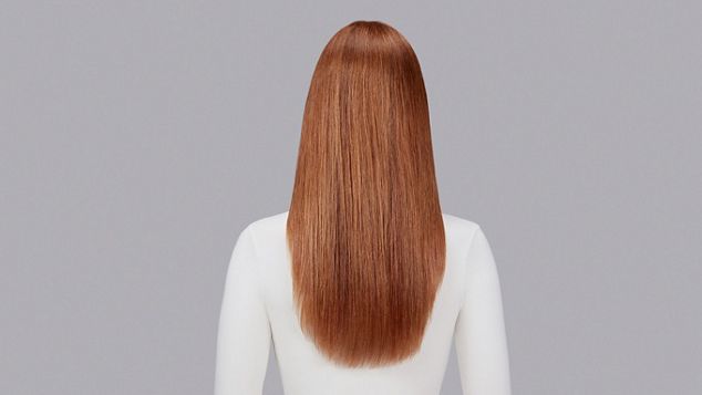 Naturlig bølgete, kastanjebrunt hår rettet med Dyson Chitosan Post-style-serum og Dyson Supersonic Nural. Sett bakfra.