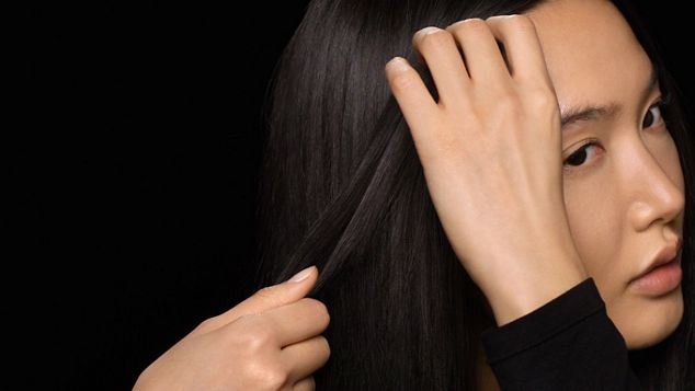 Ein Model verteilt das Produkt mit ihren Händen in ihren Haaren.
