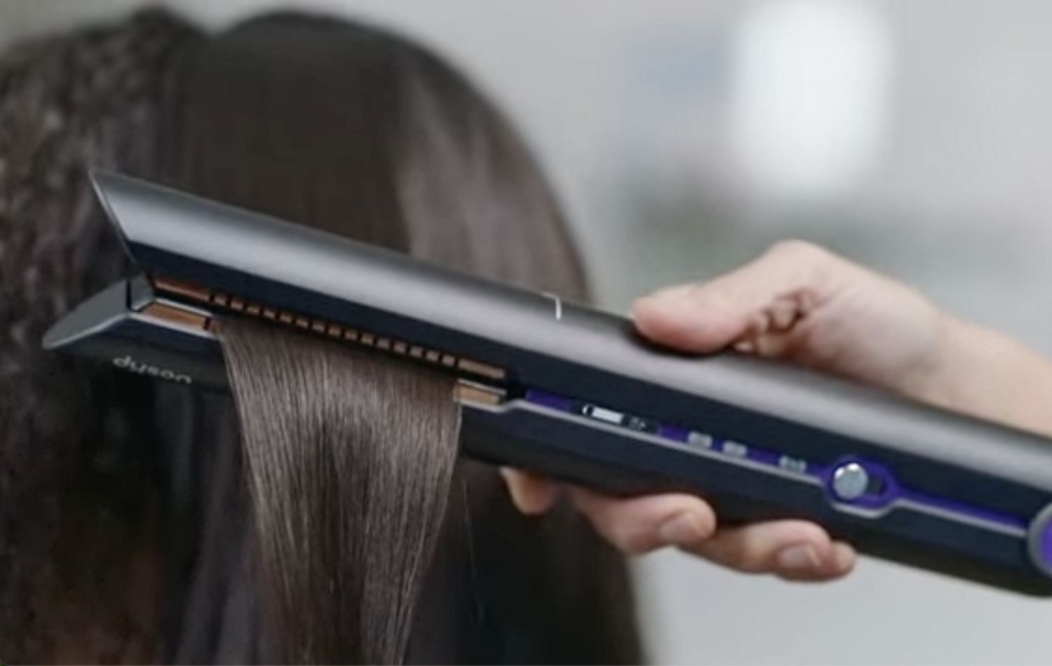 Woman using Dyson Corrale straightener with inner technology of the machine exposed.
