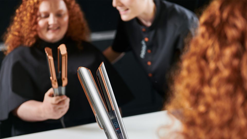 'Um cliente na loja de demonstração da Dyson experimenta o alisador Dyson Airstrait, ajudado por um especialista da Dyson.