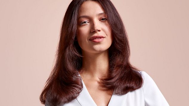 A model with mid-length brunette hair, wearing a volumised straight style.