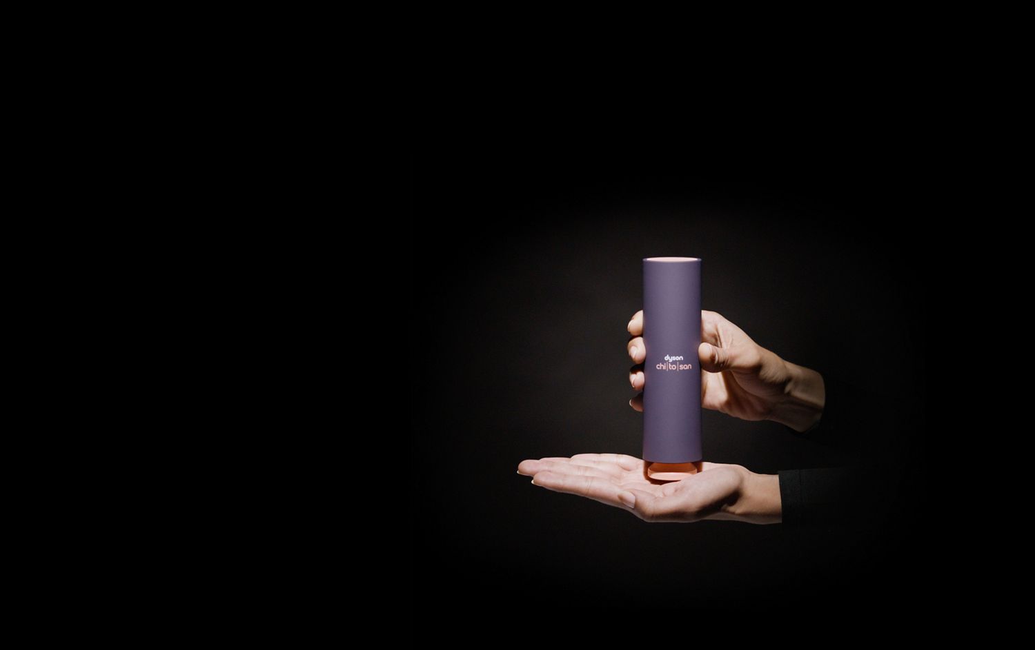Une main tient le flacon de sérum après-coiffage Dyson Chitosan, la pompe étant placée au milieu de la paume. A hand holds a bottle of Dyson Chitosan, with the pump positioned mid-palm