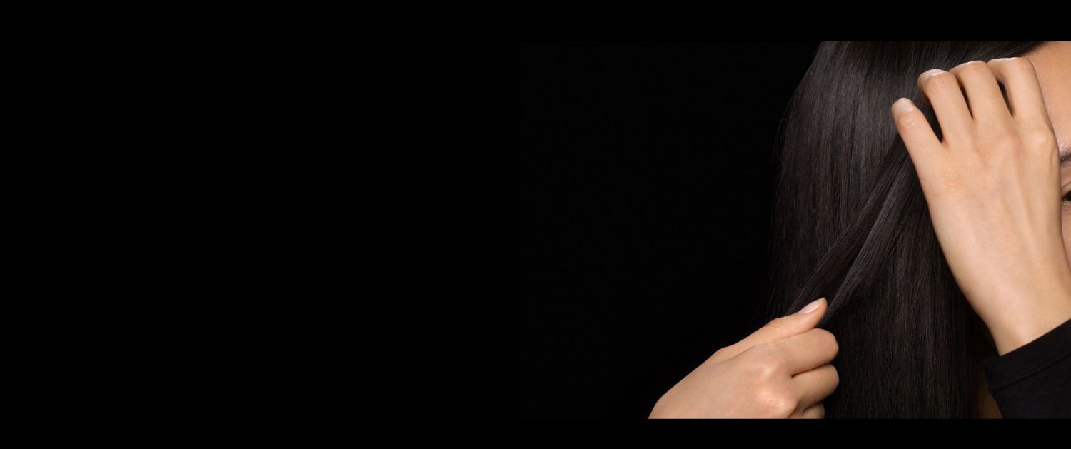 Un modèle aux cheveux humides et longs utilise ses mains pour appliquer le produit sur les longueurs. A model with long, damp hair uses her hands to smooth product through the lengths