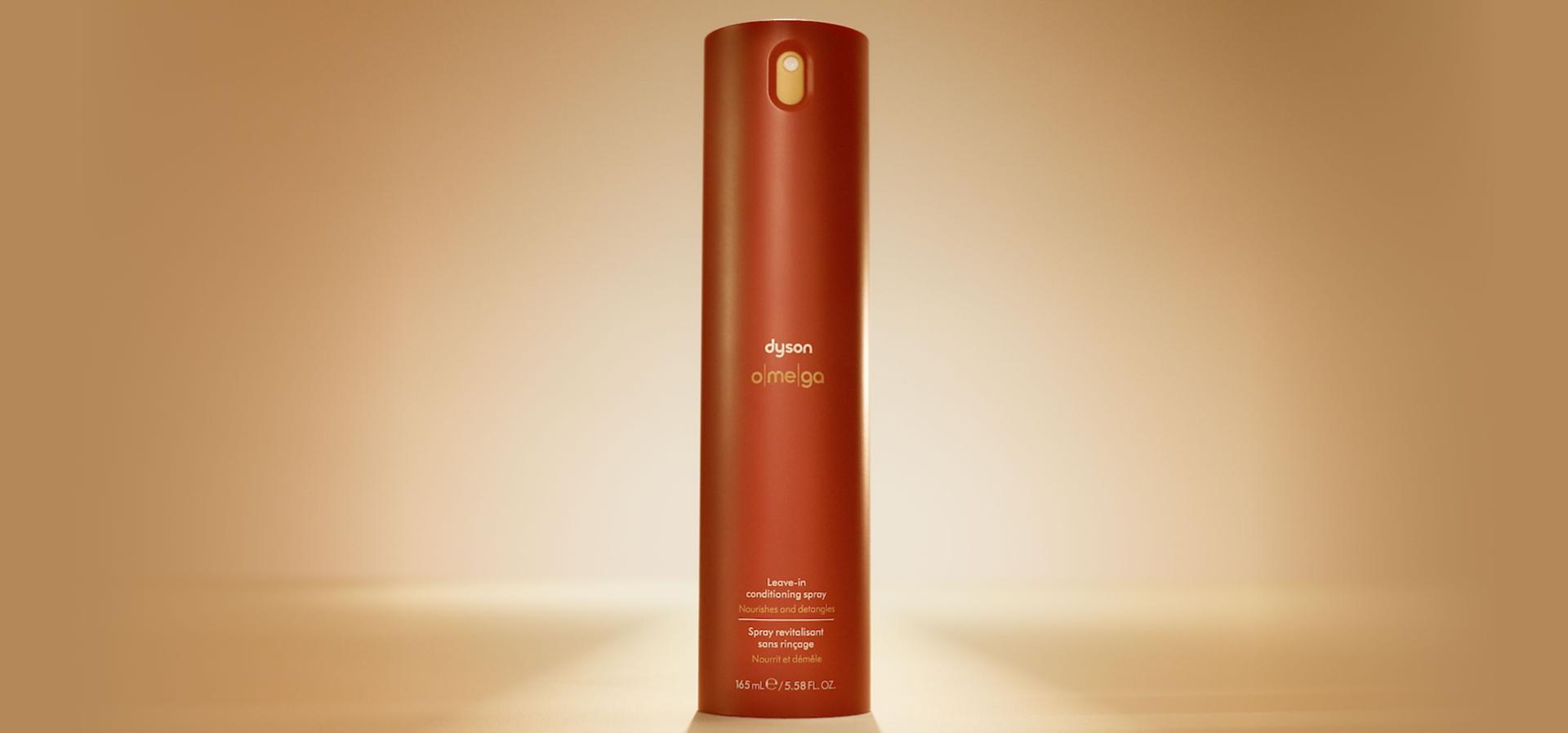 Dyson Omega leave-in conditioning spray illuminated with a warm orange glow.